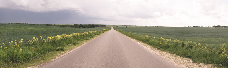 Road in the field, stormy sky