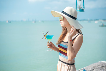 Beautiful woman is drinking ice summer drink in the beach, summer concept