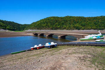 Tretboote am Ufer des Edersees und die Brücke Asel im Hintergrund, nur sichtbar bei Niedrigwasser