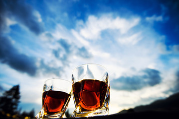 shot of whiskey at sunset dramatic sky on mountain landscape background