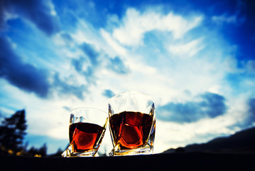 shot of whiskey at sunset dramatic sky on mountain landscape background