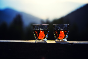 shot of whiskey at sunset dramatic sky on mountain landscape background