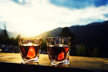 shot of whiskey at sunset dramatic sky on mountain landscape background