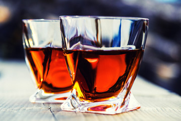 shot of whiskey at sunset dramatic sky on mountain landscape background
