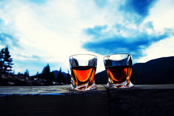 shot of whiskey at sunset dramatic sky on mountain landscape background