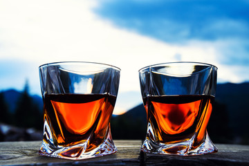 shot of whiskey at sunset dramatic sky on mountain landscape background