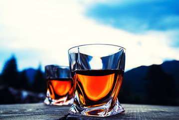 shot of whiskey at sunset dramatic sky on mountain landscape background