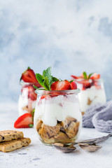 No baked dessert treifl or cheesecake with strawberries in sliced jars on an old concrete background. Selective focus.