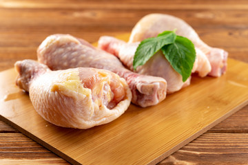 4 pieces fresh raw chicken legs on a bamboo chop board