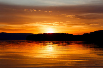 Evening sky over a mountain lake in golden color.