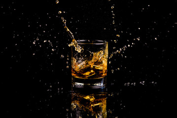 Isolated shot of whiskey with splash on black background