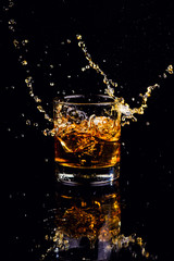 Isolated shot of whiskey with splash on black background