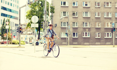people, style, leisure and lifestyle - young hipster man with shoulder bag riding fixed gear bike on city street