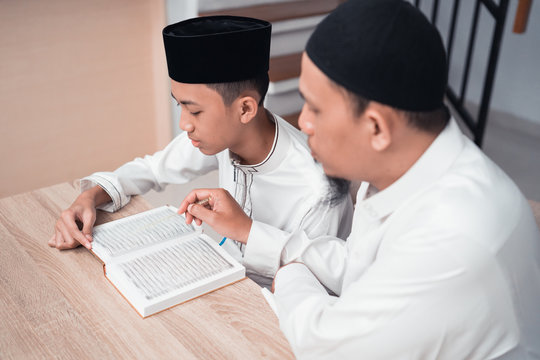 Portrait Of A Muslim Father Teaching His Son How To Read Quran