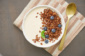 Yogurt with chocolate granola, bilberry. Breakfast on a brown table, top view