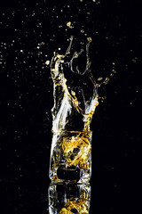 Isolated shot of whiskey with splash on black background, brandy in a glass