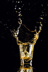 Isolated shot of whiskey with splash on black background, brandy in a glass