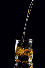 Isolated shot of whiskey with splash on black background, brandy in a glass