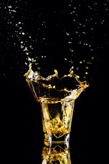 Isolated shot of whiskey with splash on black background, brandy in a glass