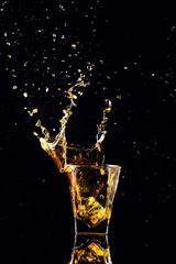 Isolated shot of whiskey with splash on black background, brandy in a glass