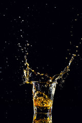 Isolated shot of whiskey with splash on black background, brandy in a glass