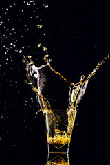 Isolated shot of whiskey with splash on black background, brandy in a glass