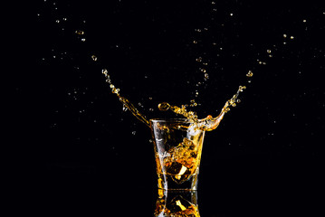 Isolated shot of whiskey with splash on black background, brandy in a glass