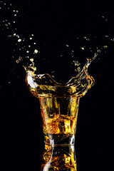 Isolated shot of whiskey with splash on black background, brandy in a glass