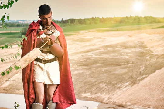Concept photo of a Roman warrior of the Colosseum in action with aggressive emotions in full military uniforms on a desert landscape on a sunny day with a dry sun.