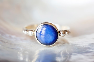 Silver ring with natural mineral sapphire gemstone on pearl background