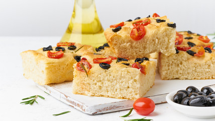 Focaccia with tomatoes, olives and rosemary, side view. Traditional Italian flat bread