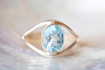 Silver ring with natural mineral topaz cut gemstone on pearl background