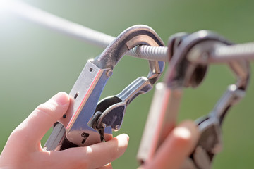 person locked safety hook on rope by hand closeup view of hiking equipment isolated on blur background security protection device outdoor sport activity and industry work authentic lifestyle concept