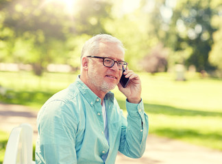 technology, senior people, and communication concept - happy old man dialing phone number and calling on smartphone at summer park