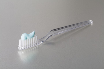 Toothbrush with toothpaste lying on silver colour background