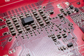 Transistors from the back of the video card under the graphic core. Macro shooting of a red microcircuit. The concept of a microscopic city.
