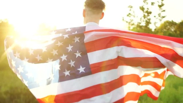 Independence Day, July 4th. Rear view of a large American flag on the shoulders of a man. The memory of the dead American soldiers, a patriotic day