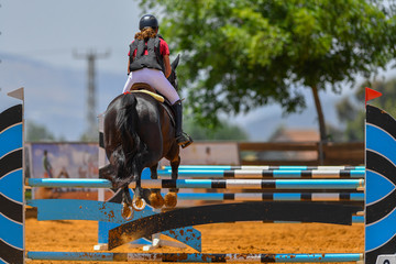 Young rider jumping over the obstacles during the horse jumping competition
