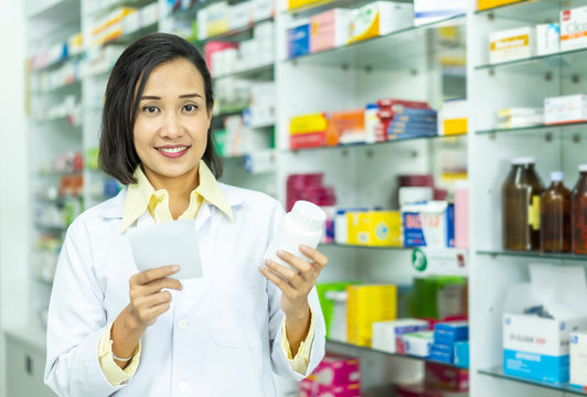 Pharmacist Asian female filling prescription medication  in pharmacy for customer or patient. small business, medicine, pharmaceutics, health care, lifestyle and people concept