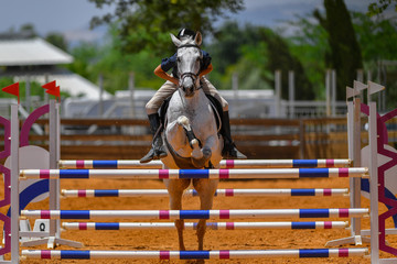 Young rider jumping over the obstacles during the horse jumping competition