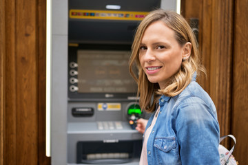 Fototapeta na wymiar Young woman taking money from ATM