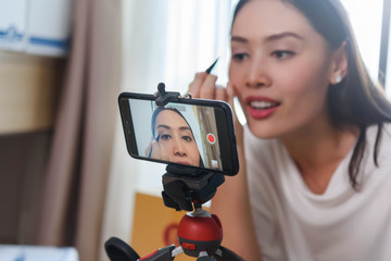 Beauty blogger demonstrating how to apply eyeliner and review products on live broadcast for social...