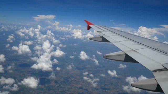 4K footage. traveling by air. aerial view through an airplane window. wing airplane and beautiful white clouds in blue sky for travel background