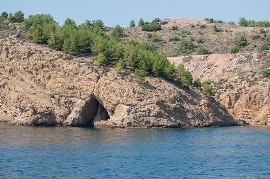 caves carved by water covered by forest seen from a boat