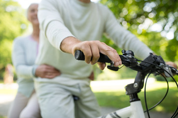active old age, people and lifestyle concept - happy senior couple riding one bicycle together at summer park