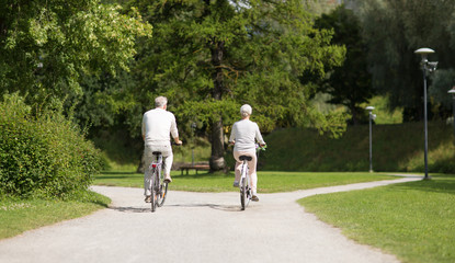 active old age, people and lifestyle concept - happy senior couple riding bicycles at toom park in summer city of tallinn, estonia