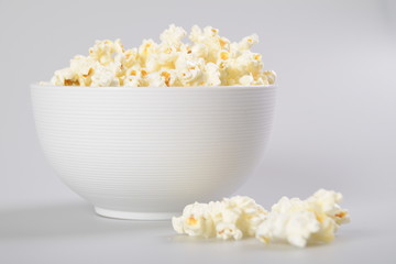 Caramel popcorn in white bowl on white background.