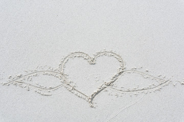 Drawn love heart shape on white sand beach background