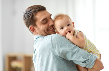 family, fatherhood and people concept - happy father holding little baby daughter at home