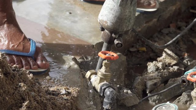 Closeup of plumber fixing service,4K video . Worker drilling concrete floor  with jackhammer repairing leakage of underground  water pipeline.   